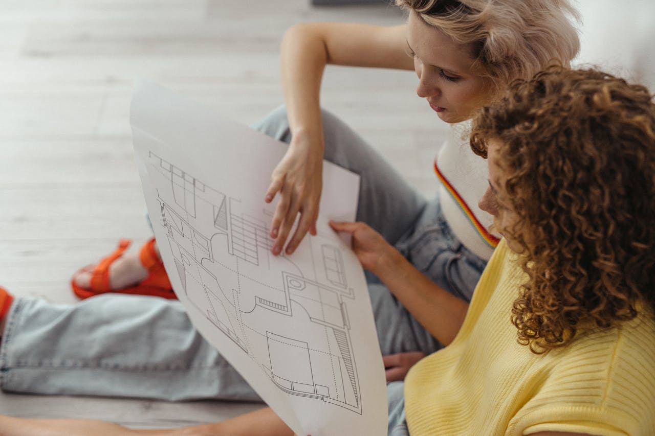 Two women discussing and planning with a floor plan indoors.